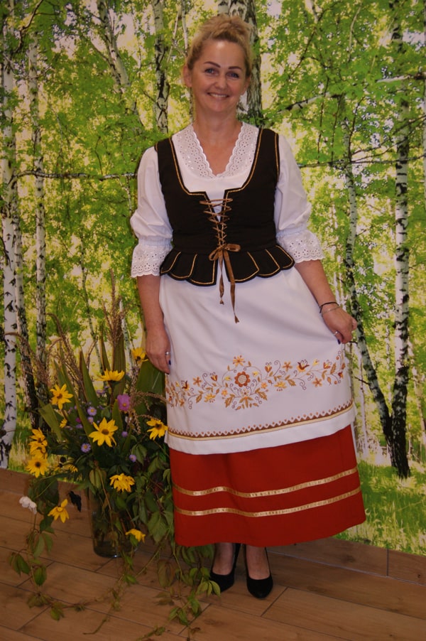 Hanna Kwaśniewska  w stroju borowiackim na tle brzóz