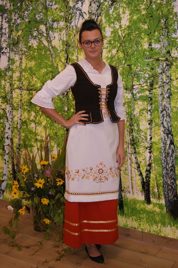 Kamila Andrearczyk  w stroju borowiackim na tle brzóz