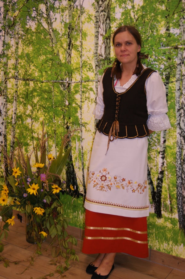 Mariola Maciejak  w stroju borowiackim na tle brzóz