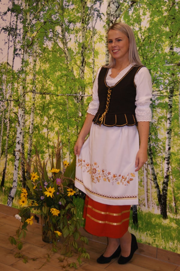 Milena Węsierska  w stroju borowiackim na tle brzóz